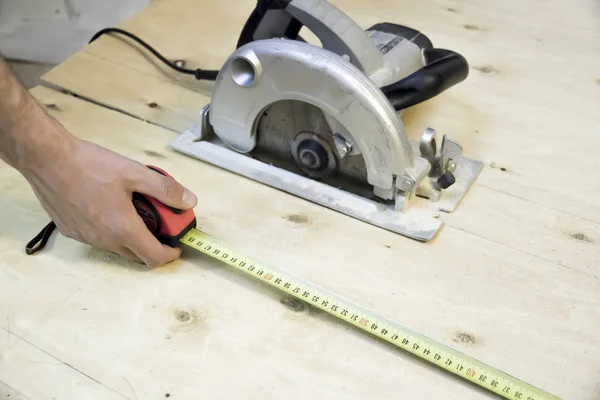 Línea de cinta métrica manual sobre fondo de sierra circular de madera contrachapada — Foto de Stock