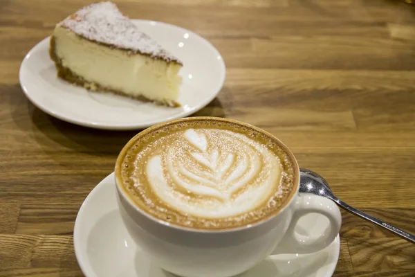 Cappuccino em caneca contra pedaço de bolo — Fotografia de Stock