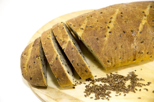 Loaf of flax on wooden board is cut into pieces — Stock Photo, Image