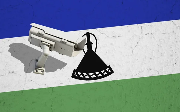 Lesotho flag on wall with CCTV security surveillance camera. Concept political relations with neighbors