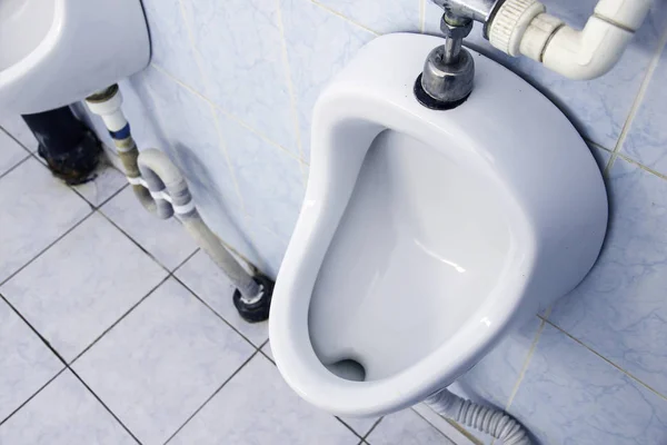 Witte urinoirs op de betegelde muur in mannelijke toilet — Stockfoto