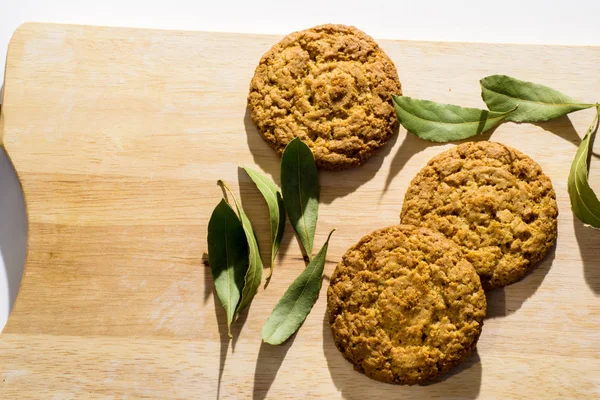 Oat cookies on wooden table with bay leaves — Stock Photo, Image