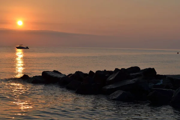 O pôr-do-sol de verão sobre o mar. Barco e pedras — Fotografia de Stock