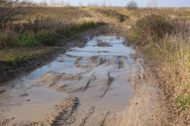 Geçilemez toprak yol. Yoldaki çamur ve su birikintisi