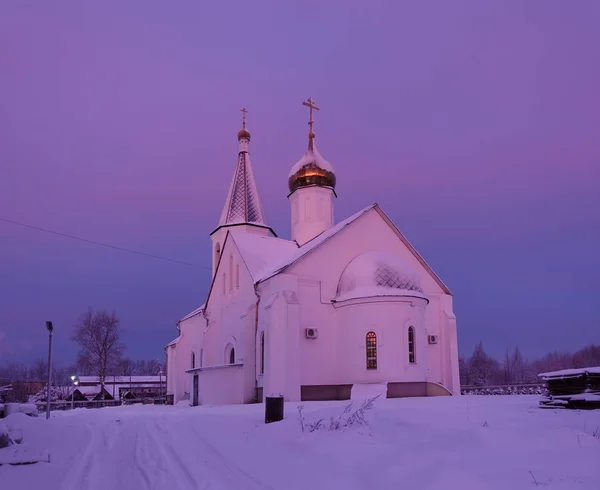 Frostiger Wintermorgen. Die Kirche ist in rosa und lila Morgenrot erleuchtet. Russland — Stockfoto