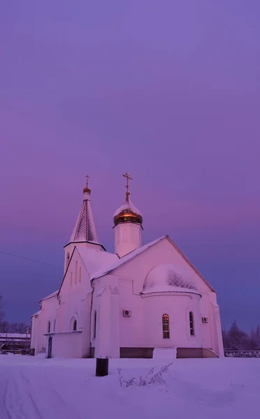 Frostiger Wintermorgen. Die Kirche ist in rosa und lila Morgenrot erleuchtet. Russland — Stockfoto