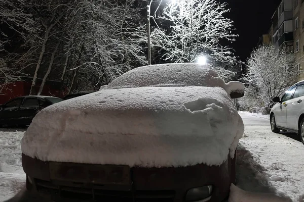 Noite de inverno na cidade. Os carros são cobertos com uma espessa camada de neve. Rússia Imagens De Bancos De Imagens