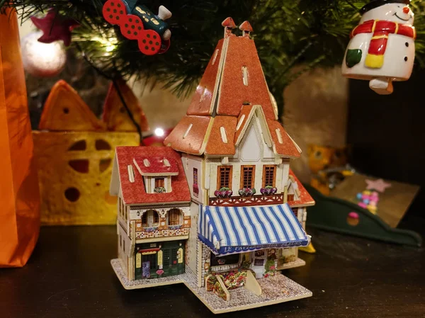 Weihnachtskomposition mit Spielzeug, einem Holzhaus unter dem Baum. — Stockfoto