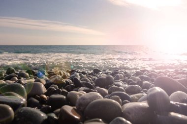 Çakıl taşlı deniz kıyısı. Sahilde ıslak deniz taşları ve sessiz deniz sörfü.