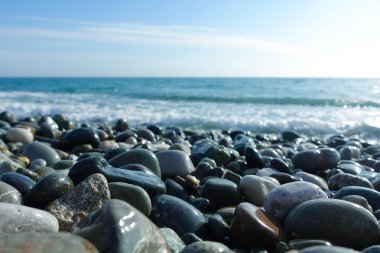 Çakıl taşlı deniz kıyısı. Sahilde ıslak deniz taşları ve sessiz deniz sörfü.