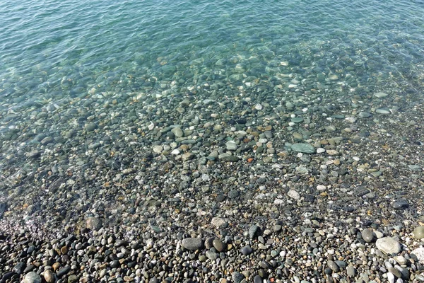 Sea stones in the sea water. Pebbles under water. The view from the top. Nautical background. Clean sea water. Transparent sea.