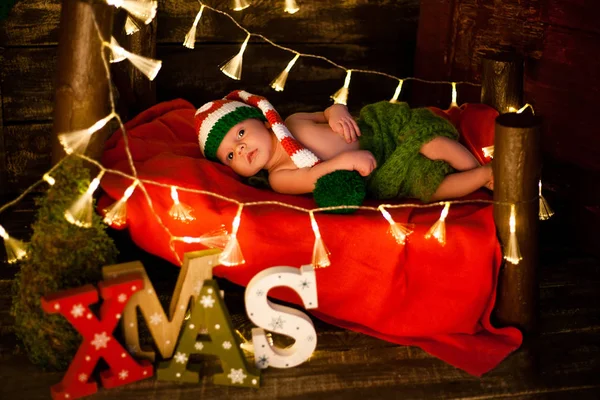 Bebé acostado en manta roja en cuna en Navidad . —  Fotos de Stock