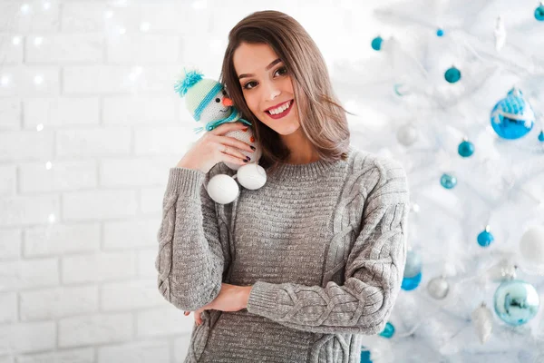 Retrato de niña feliz con un muñeco de nieve cerca del árbol de Navidad blanco —  Fotos de Stock