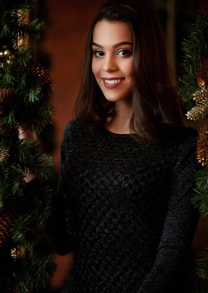 Noel ağacı yakınındaki siyah elbiseli gülümseyen kız portresi — Stok fotoğraf