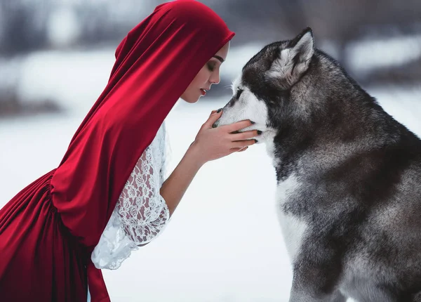 Girl in costume Little Red Riding Hood with dog malamute like a