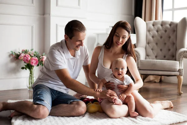 Glad ung familj med små barn sitter på golvet. — Stockfoto