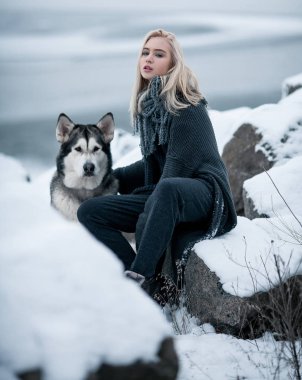 Köpek Malamute kış kayalarda arasında ile kız. 