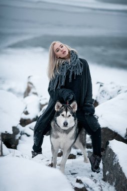 Köpek Malamute kış kayalarda arasında ile kız.