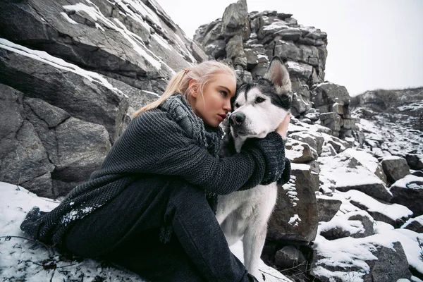 Lány kutya Malamute télen sziklák között. Közelről. — Stock Fotó