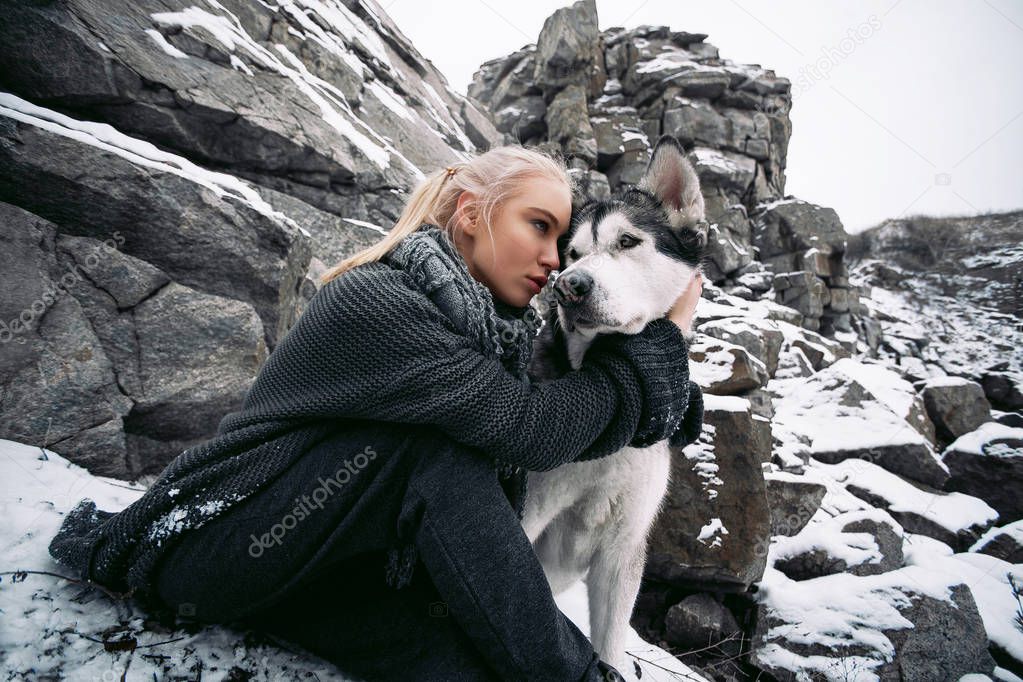 Girl with dog Malamute among rocks in winter. Close up.