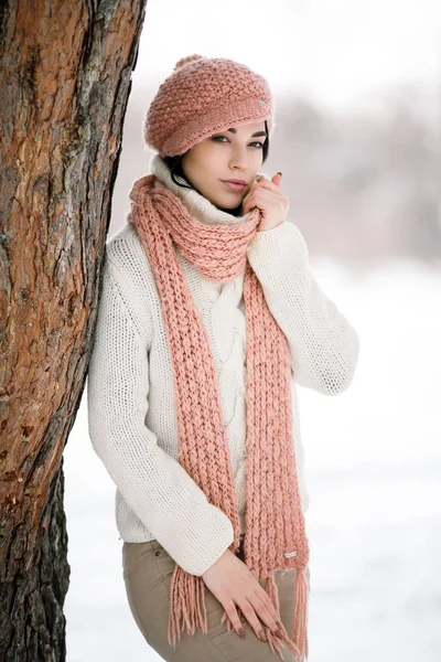 Dziewczyna w sweter czapka i szalik w pobliżu drzewa w lesie zimą — Zdjęcie stockowe