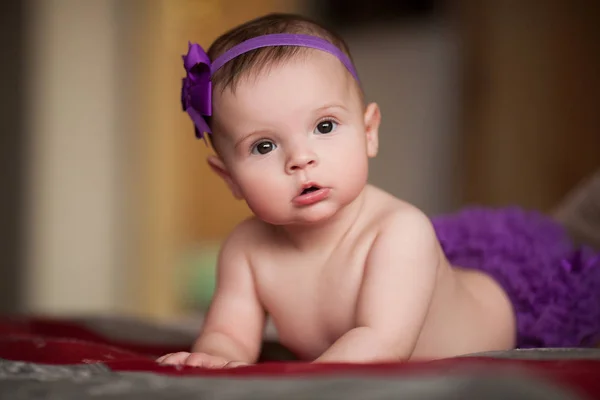 Портрет маленького ребенка с венком из фиолетовой ленты с цветком на голове . — стоковое фото
