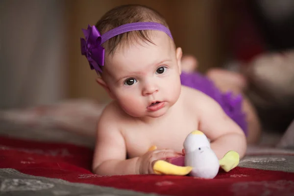 Portrait d'une petite enfant avec une couronne de ruban violet avec des fleurs sur la tête . — Photo