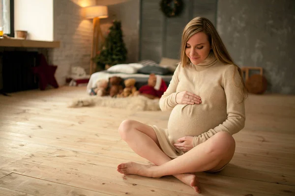 Mujer embarazada se sienta y sostiene sus manos alrededor del vientre . —  Fotos de Stock