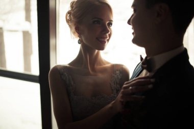 Gelin ve damat pencere arka plan üzerinde gülümseyen portresi.