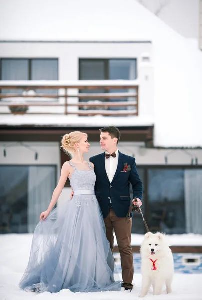 Bride and groom in winter with dog in snow. — Stock Photo, Image