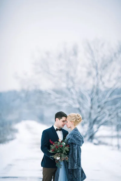 Bruden och brudgummen bland snöiga landskap. — Stockfoto