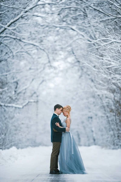Noiva e noivo entre estrada nevada na floresta . — Fotografia de Stock