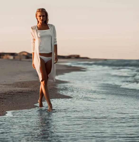 Girl in white tee-shirt and bikini on sea background.