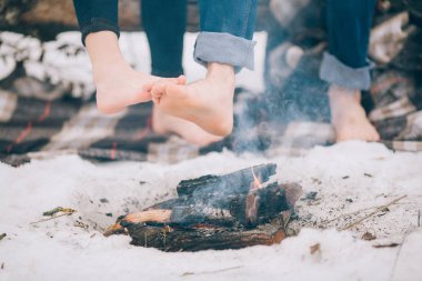 Genç kadın ve erkek kış piknik ateşte çıplak ayak sıcak. 