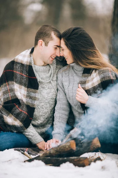 Joven mujer y el hombre están en frente de fumar hoguera en invierno pi — Foto de Stock