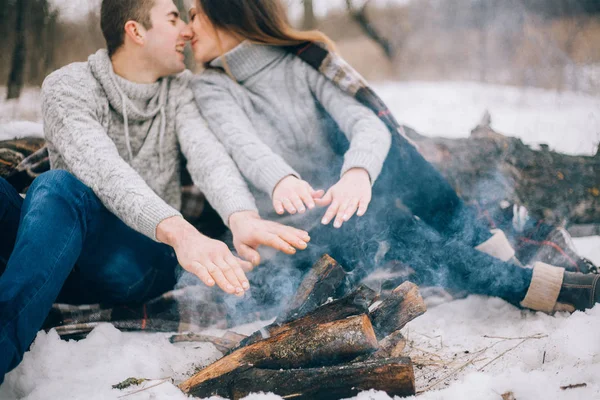 Jovem mulher e homem aquece as mãos sobre a fogueira durante o inverno — Fotografia de Stock