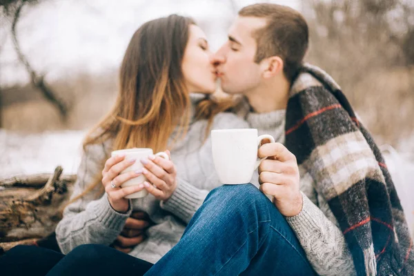 Jonge vrouw en man zijn kussen op winter picknick. — Stockfoto