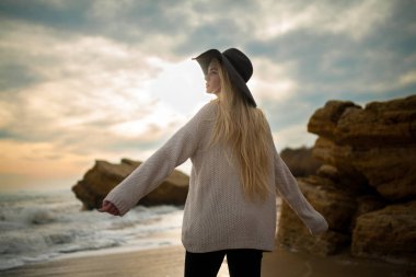 Kadın şapka ve gün batımında kış sahilde kazak.