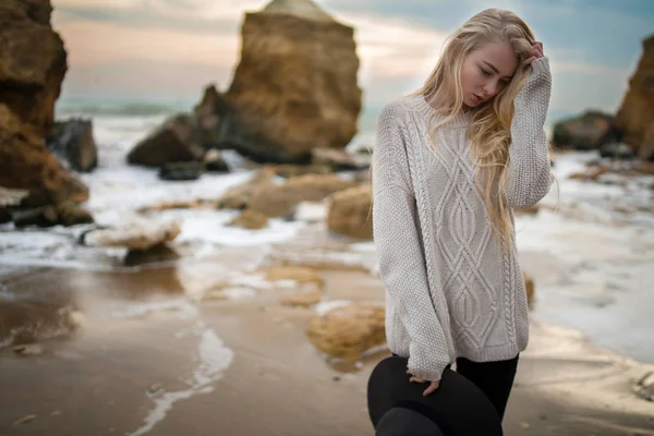 セーターと帽子に夕暮れ時の冬の浜辺の女. — ストック写真