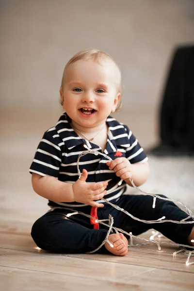 Kis baba ül a fa padló, és játszik a fény koszorú — Stock Fotó