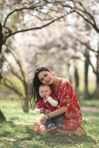 Genç anne bebeğini yürüyüşte bahar bahçe ile. — Stok fotoğraf