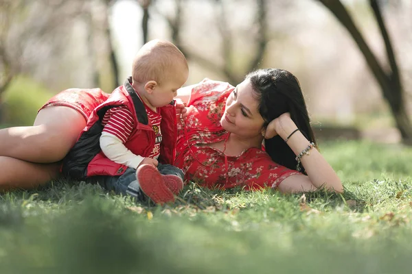 Junge Mutter mit Baby auf Spaziergang im Frühlingsgarten. — Stockfoto