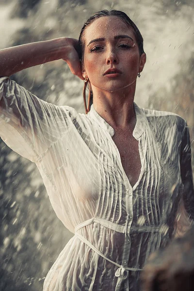 Giovane donna ritratto in camicia bianca bagnata vicino alla cascata . — Foto Stock