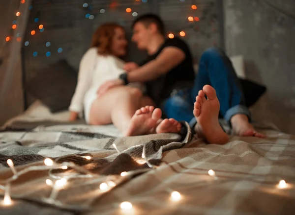 Молодые влюбленные женщина и мужчина сидят бок о бок на кровати и обнимаются . — стоковое фото