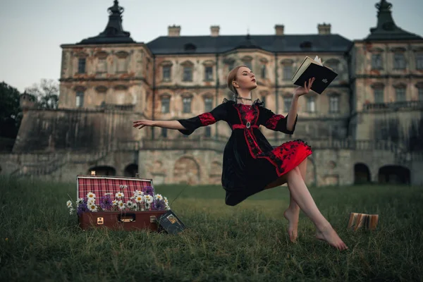 Zauberin fliegt durch die Luft und liest Buch vor der Kulisse einer alten Burg. Levitation. — Stockfoto