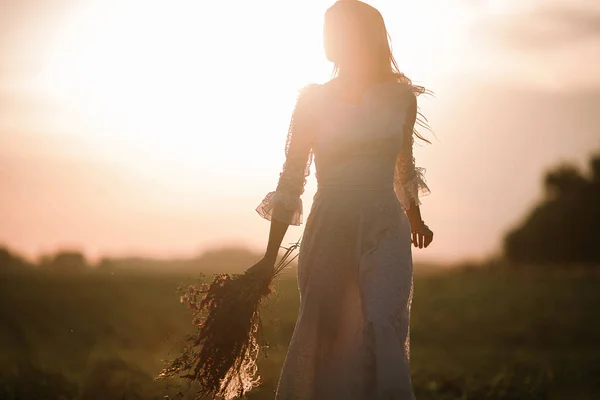 Giovane donna in abito lungo pizzo bianco su campo di grano al tramonto . — Foto Stock