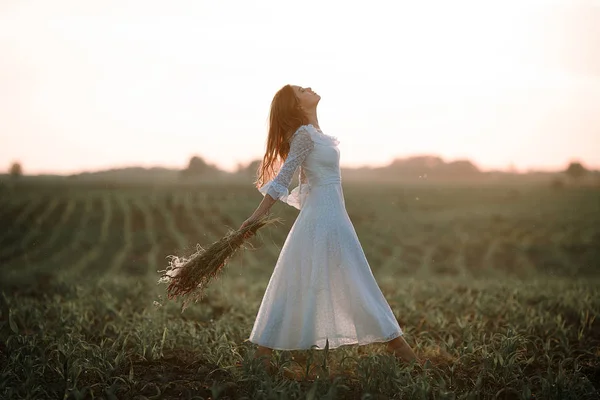 在长长的白色花边礼服对玉米田的年轻女人。侧视图. — 图库照片