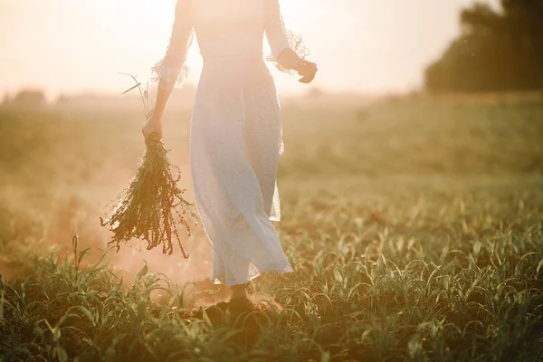 Jonge vrouw in lange witte lace dress op cornfield bij zonsondergang. — Stockfoto