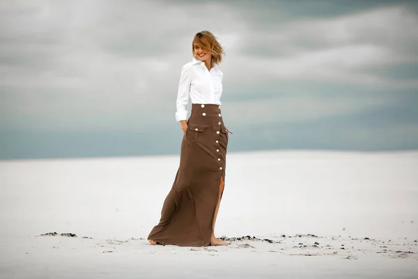 Young woman stands on sand in desert and smiles. — Stock Photo, Image