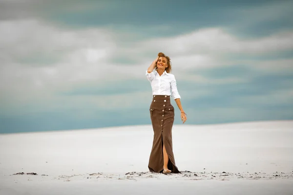 Jonge vrouw gaat barefoot op zand in de woestijn en glimlacht. — Stockfoto